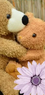 Two teddy bears with a purple flower on a wooden log.