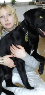 Woman holding her black dog in a cozy home setting.