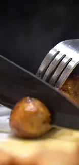 Close-up of knife and fork slicing a piece of brown meat on a plate.