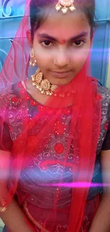 Girl in traditional red attire with intricate jewelry posing near a blue door.