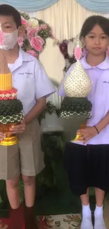 Children in traditional attire holding cultural crafts.