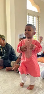 A child in pink traditional attire at a cultural gathering.