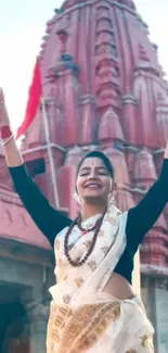 Joyful woman in traditional attire with historic temple backdrop.