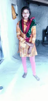 Portrait of a person in traditional attire standing inside a rustic home.