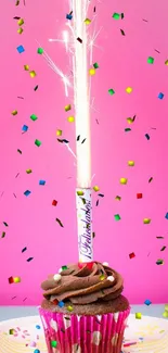 Chocolate cupcake with sparkler on pink backdrop.