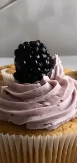 Cupcake with blackberry frosting and decorative topping.