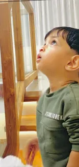 Child gazing up near a window indoors, curious and thoughtful.