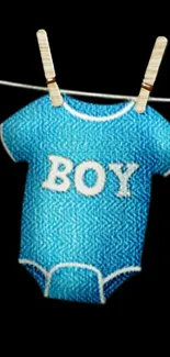 Blue baby boy onesie hanging on a line, black background.