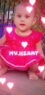 Cute baby in red dress with heart shapes.