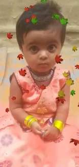 Cute baby in peach festive dress with colorful autumn leaves.