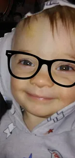 Adorable baby in hood with novelty glasses, smiling.