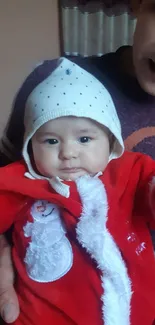 Cute baby in red Santa outfit with festive hat.