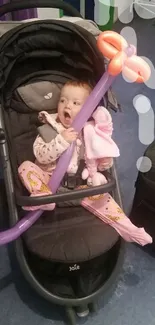 Cute baby in a stroller with a balloon, joyful expression, and a fun atmosphere.