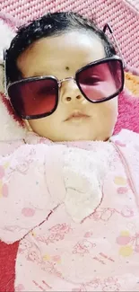 Baby with sunglasses on a colorful playmat.