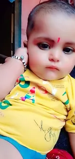 Adorable baby with expressive eyes, wearing colorful attire.