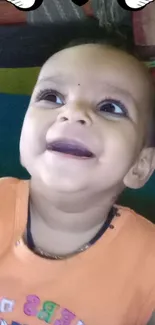 Smiling baby with birds and heart decoration above.