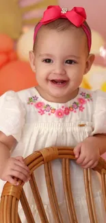 Cute baby with floral dress and pink headband.