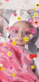 Cute baby with floral sunglasses and pink blanket in a flower-filled background.