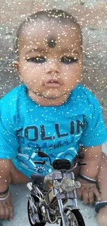 Baby in blue shirt with motorcycle and sparkles.