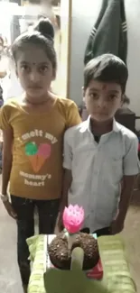 Kids celebrating birthday with cake indoors.