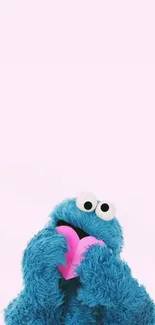 Wallpaper of a blue monster holding a pink heart on a light pink background.