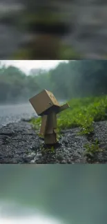 Cardboard box figurine on misty road with forest background.