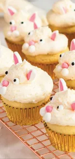 Cute bunny cupcakes with cream frosting on a cooling rack.