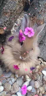 Fluffy bunny adorned with pink flowers sitting among rocks.