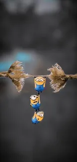 Three cartoon characters hanging on a rope, against a blurred gray background.