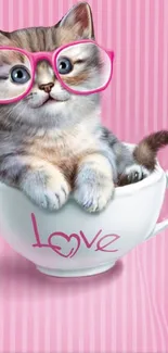 Cute kitten with pink glasses in a teacup on a striped pink background.