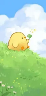 Cute yellow chick on a green hill under a blue sky.