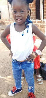 Smiling child in casual outfit with blue jeans and red sneakers.