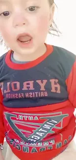 Child in colorful red and blue shirt with open mouth expression.