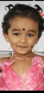 Adorable child in pink dress smiling happily.