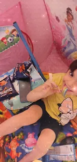 Child playing in a decorative tent with toys and smiling brightly.