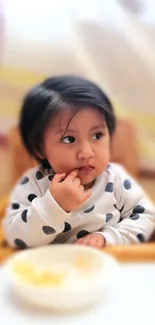 Cute child in polka dot sweater sitting in a high chair, creating a cozy atmosphere.