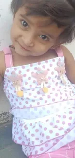 Adorable child with a cute smile in a pink polka dot dress.