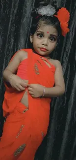 Adorable child in red traditional outfit with dark background.