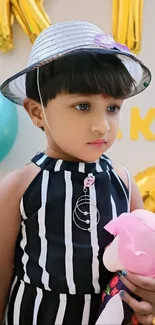 Cute child in striped dress with hat and plush toy.