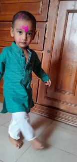 Young child in colorful traditional attire with wooden background.