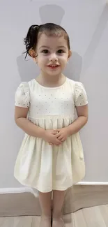 Adorable child in a cream dress smiling at the camera.