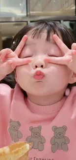 Cute child in pink sweater with peace sign pose.