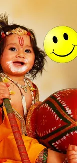 Adorable baby in traditional attire holding a decorative drum with a smiley face.