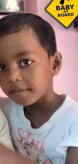 Child smiling with 'Baby on Board' sign.