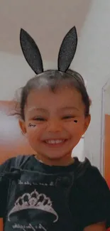 Smiling child wearing cute black bunny ears and a black shirt.