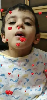 Young child with red heart accents on wallpaper.