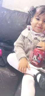 Child with Minnie Mouse bottle on sofa.