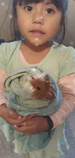 Child holding a guinea pig wrapped in a towel.