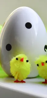 Yellow fluffy chicks with a large white egg on display.
