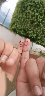 Cute smiling faces drawn on fingers against a leafy green background.